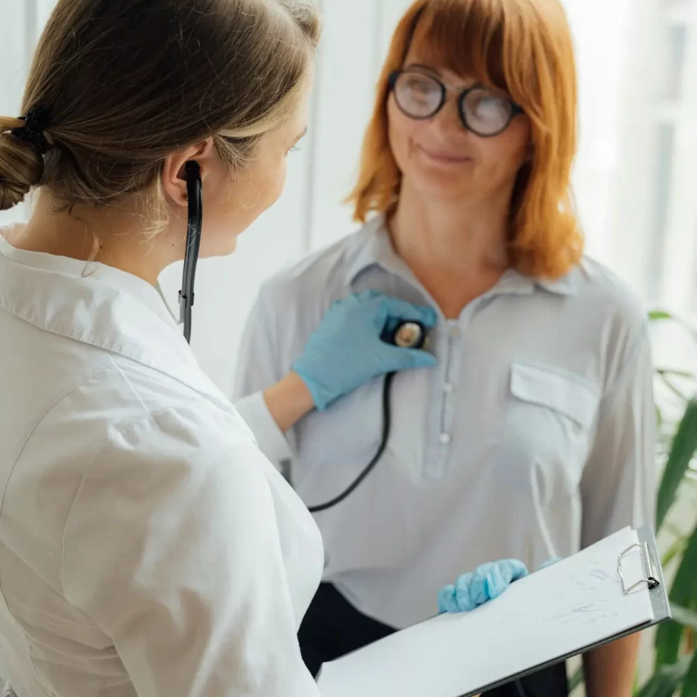 Doctor with stethoscope performing checkup on patient indoors.