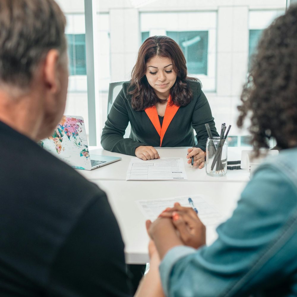 A couple signing adoption papers in an office with a lawyer's assistance.